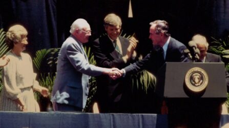 President john f kennedy shakes hands with a group of people.