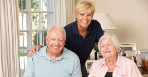 A senior man and a woman are posing for a photo in a living room.