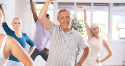 A group of older adults engaged in yoga, a form of movement beneficial for seniors as it promotes flexibility and relaxation in a dedicated space for care options.