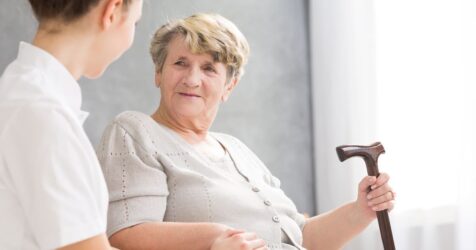 A nurse is addressing an elderly woman with a cane about senior living safety.