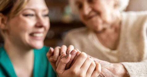 A woman is holding an elderly woman's hand.