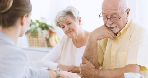 An older man is talking to an older woman at a table.