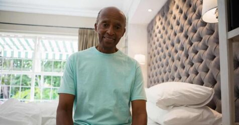 An older adult lounging on a bed in a hotel room, preparing for a restful sleep.