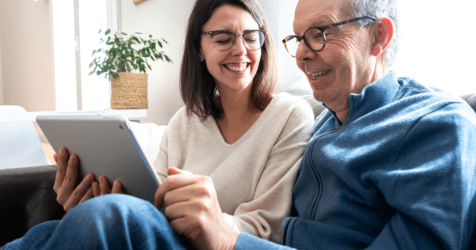 Adult female and senior male on sofa with tablet.